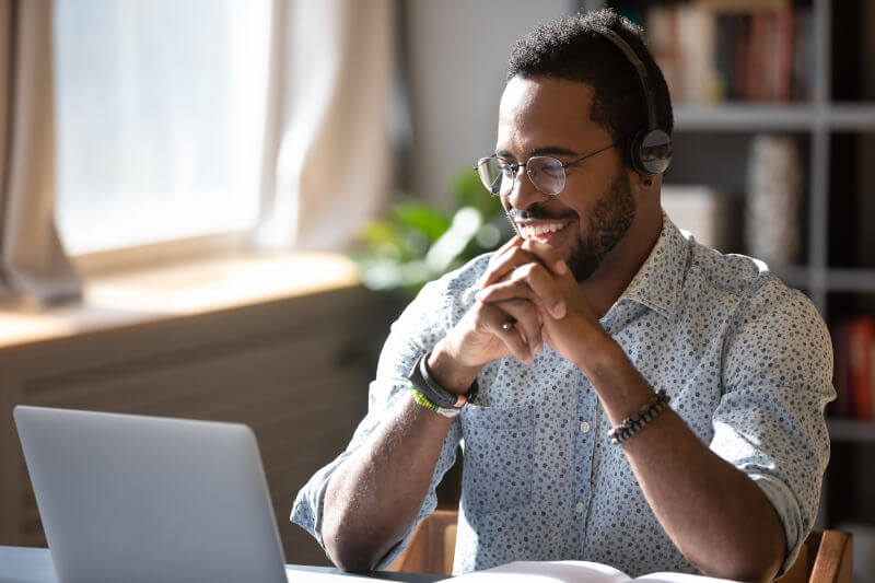 Happy millennial using headphones and laptop